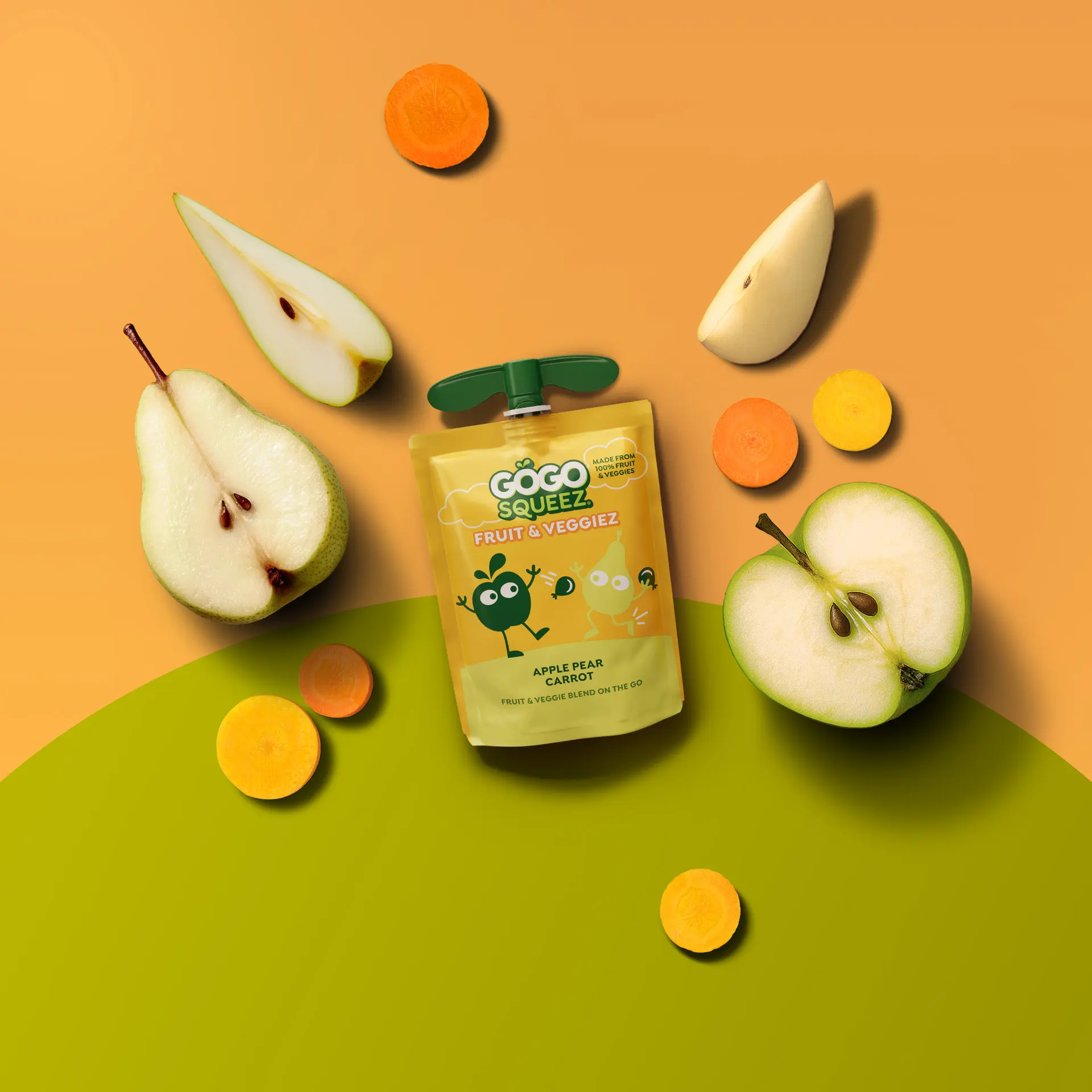 GoGo squeeZ Fruit & VeggieZ pouch in the flavor apple pear carrot on a green and orange backdrop with real carrot slices and fresh pear and apple beside it.
