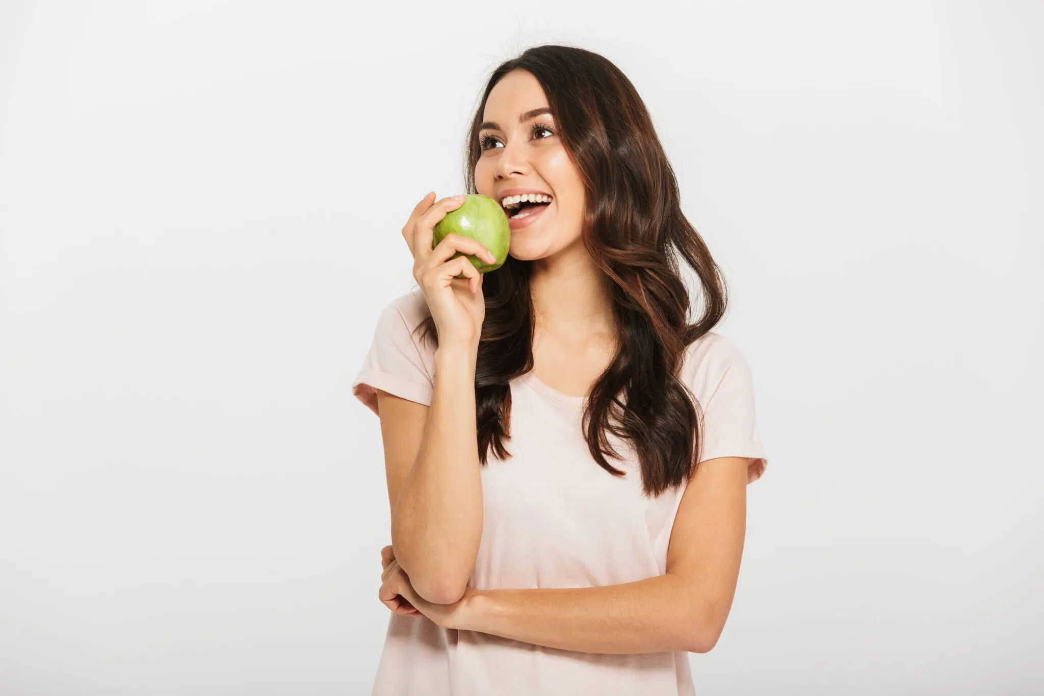 Woman smiling and holding a green apple near her mouth