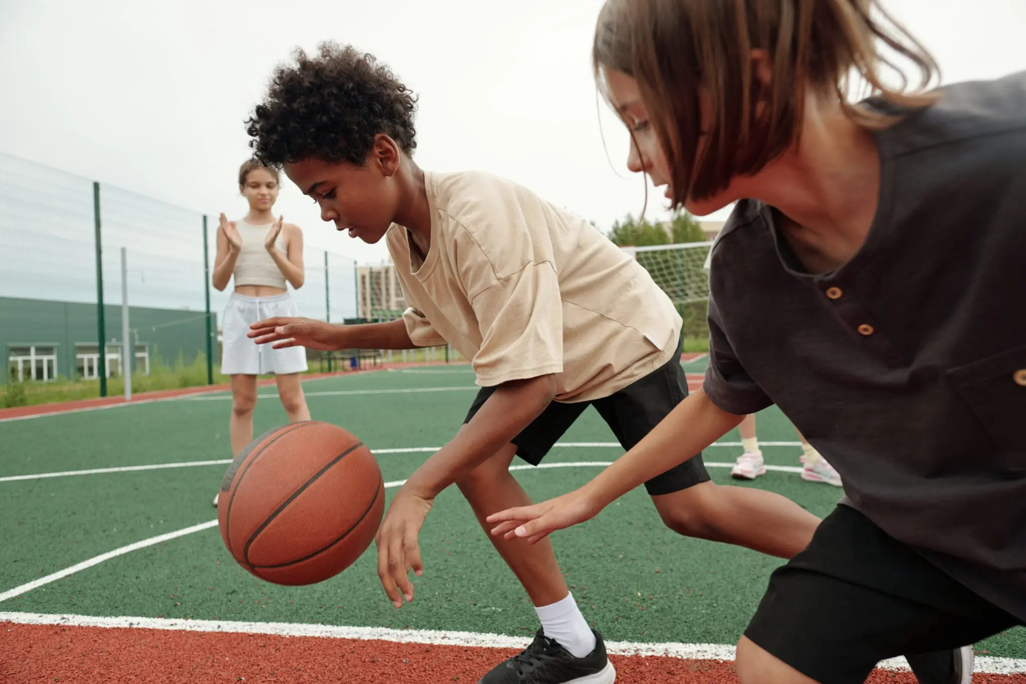 African,American,Schoolboy,In,Activewear,Dribbling,Ball,While,Running,Forwards Three children playing basketball outdoors.