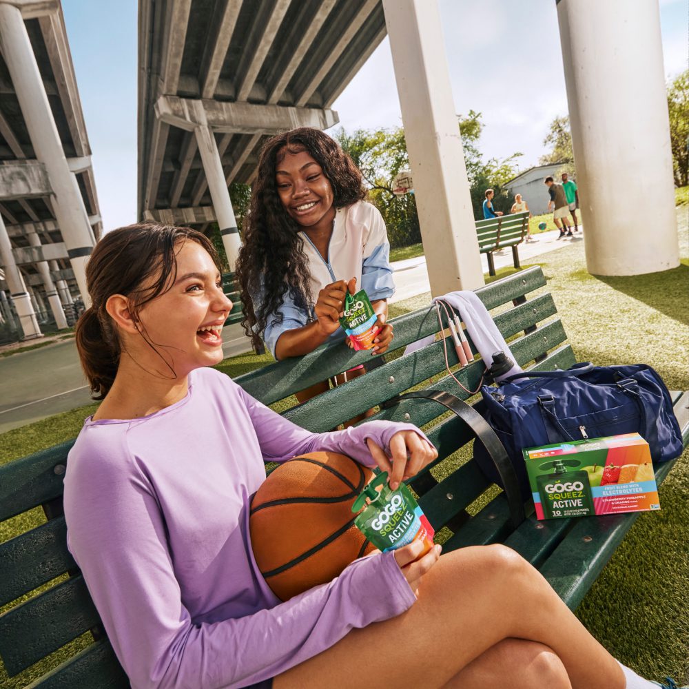 Teens playing basketball eating GoGo squeeZ Active With Electrolytes
