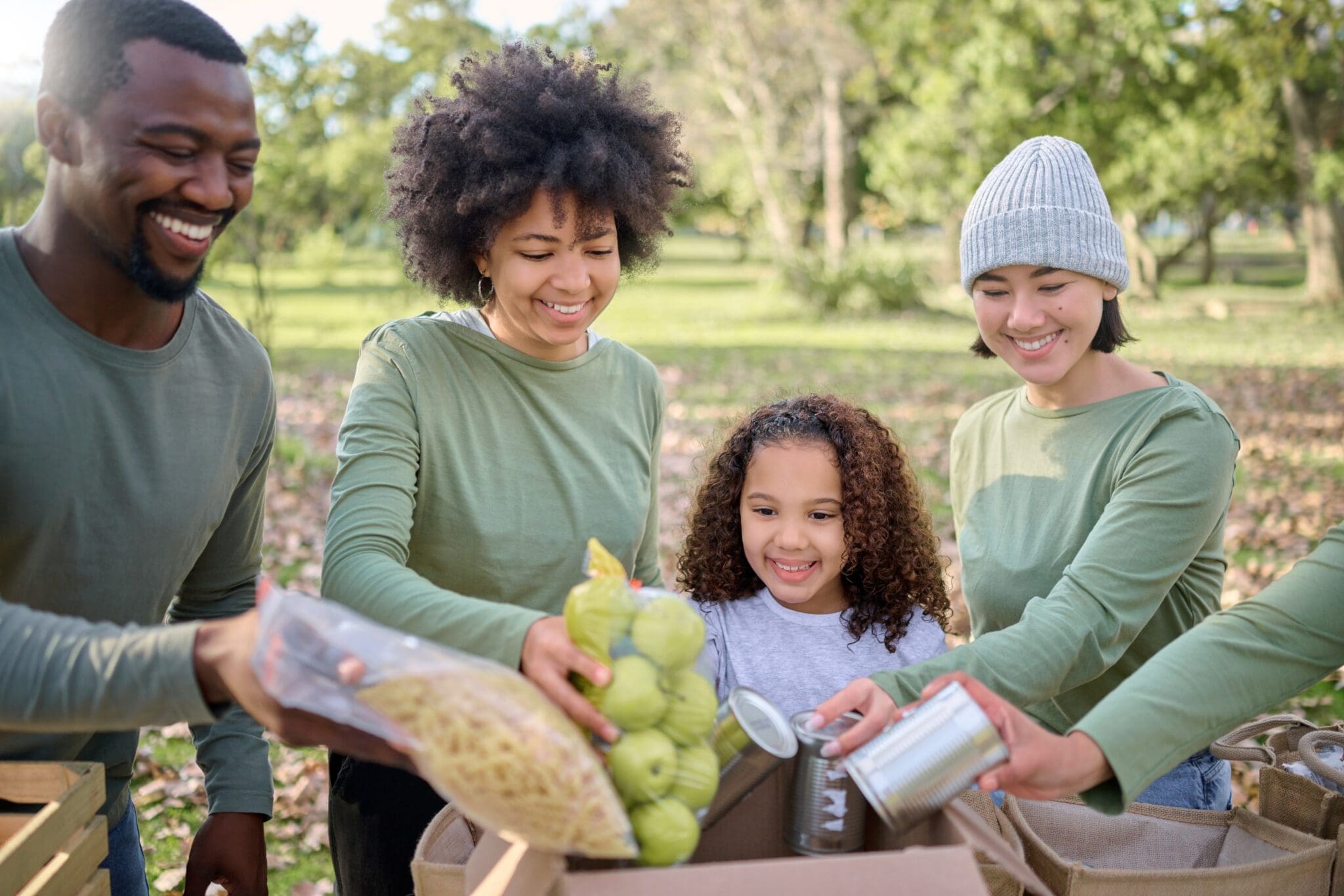 A family of 2 adults and 2 children donating food by placing it in a box